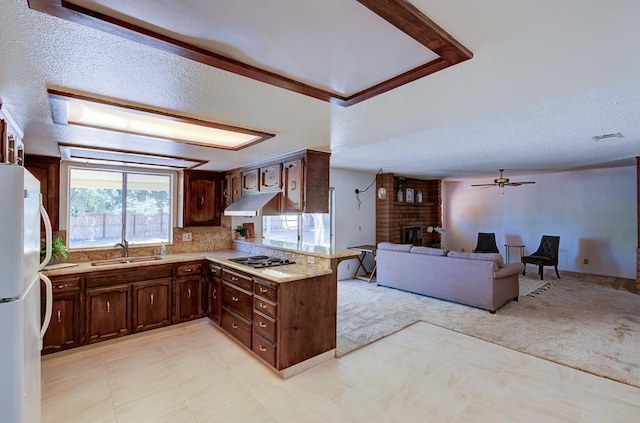 41151 Fig Grove Cir, Madera, CA 93636 - kitchen featuring freestanding refrigerator, light countertops, cooktop, open floor plan, and a brick fireplace