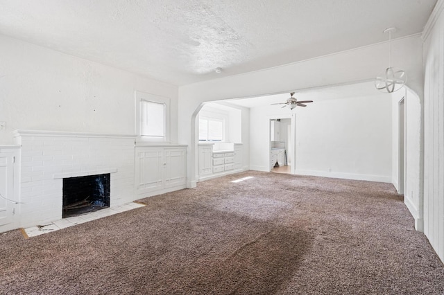 3334 E Montecito Ave, Fresno, CA 93702 - unfurnished living room with carpet, a textured ceiling, a brick fireplace, ceiling fan, and arched walkways