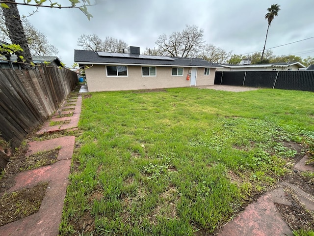 1223 E Drummond Ave, Fresno, CA 93706 - back of house featuring stucco siding, a fenced backyard, roof mounted solar panels, and a patio