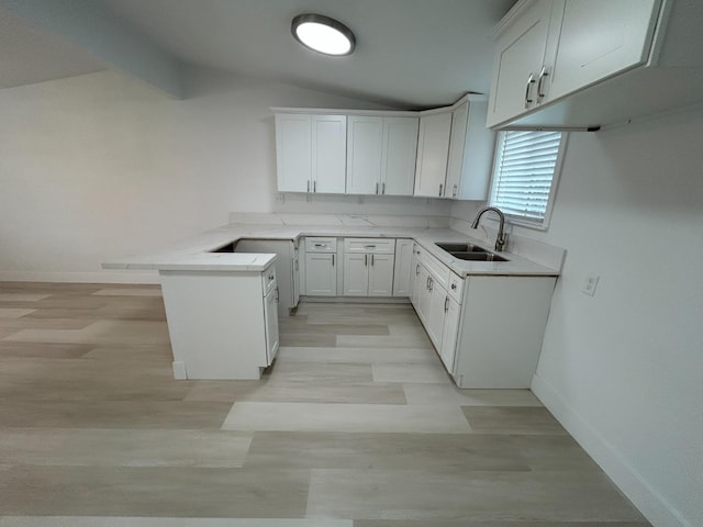 1223 E Drummond Ave, Fresno, CA 93706 - kitchen with lofted ceiling, a peninsula, light wood finished floors, white cabinetry, and light countertops