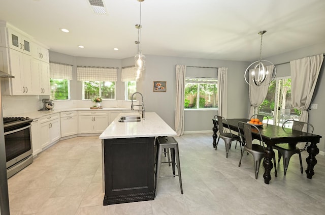1082 E Oakmont, Fresno, CA 93730 - kitchen featuring gas range, white cabinetry, a kitchen island with sink, glass insert cabinets, and hanging light fixtures
