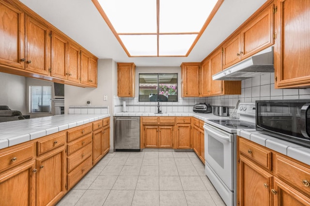 115 Prince Ln, Madera, CA 93637 - kitchen with dishwasher, white electric stove, under cabinet range hood, black microwave, and backsplash