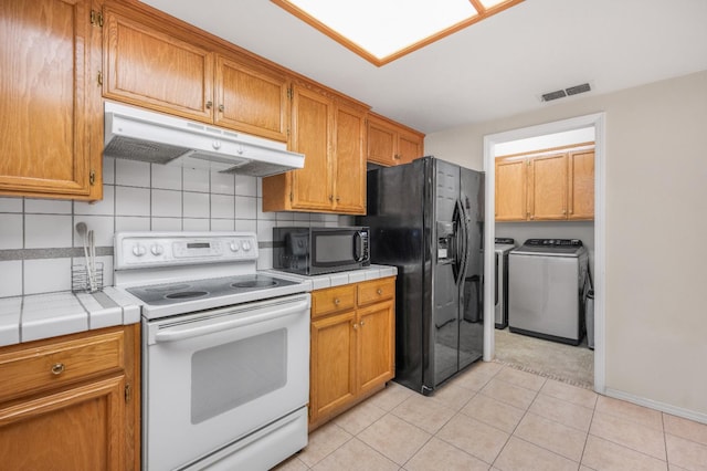 115 Prince Ln, Madera, CA 93637 - kitchen featuring black appliances, under cabinet range hood, washing machine and dryer, and tile countertops