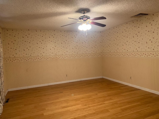 6924 N Winery, Fresno, CA 93710 - empty room with light wood finished floors, a wainscoted wall, ceiling fan, and a textured ceiling