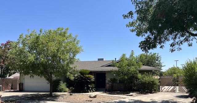 6924 N Winery, Fresno, CA 93710 - view of property hidden behind natural elements featuring a garage, driveway, brick siding, a gate, and roof with shingles