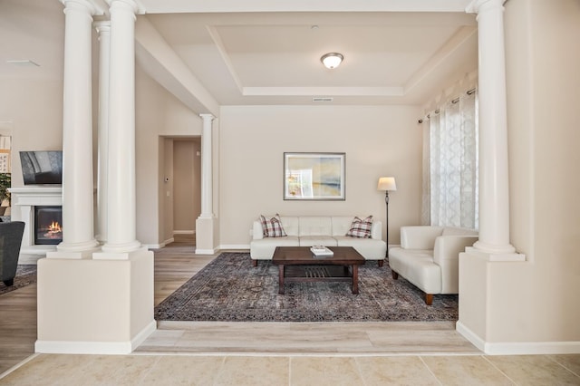 10911 E Swift Ave, Clovis, CA 93619 - living area featuring a tray ceiling, decorative columns, a glass covered fireplace, and wood finished floors