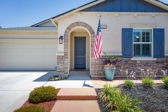 629 Del Monte Ave, Clovis, CA 93619 - doorway to property with board and batten siding, stone siding, concrete driveway, and a garage