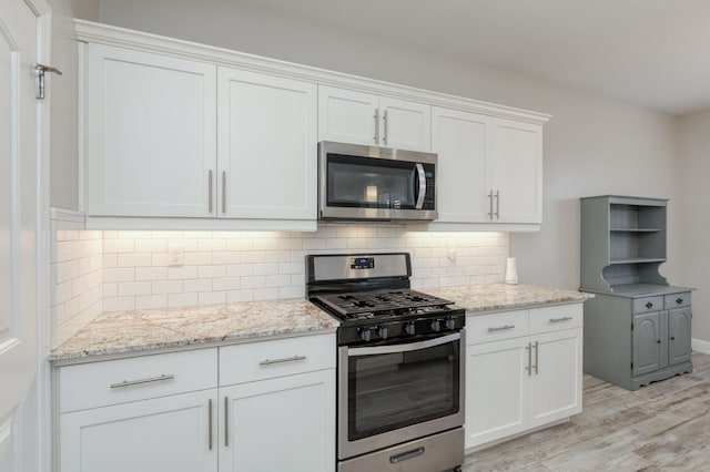 629 Del Monte Ave, Clovis, CA 93619 - kitchen featuring stainless steel appliances, light wood-style floors, white cabinetry, light stone countertops, and decorative backsplash