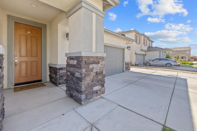 1066 Jade Way, Lemoore, CA 93245 - doorway to property featuring stucco siding, concrete driveway, stone siding, and an attached garage