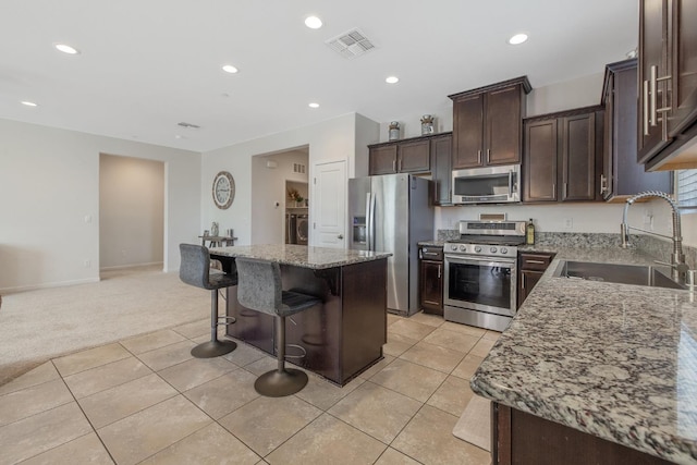 1066 Jade Way, Lemoore, CA 93245 - kitchen with stainless steel appliances, a center island, light colored carpet, light tile patterned floors, and dark brown cabinets