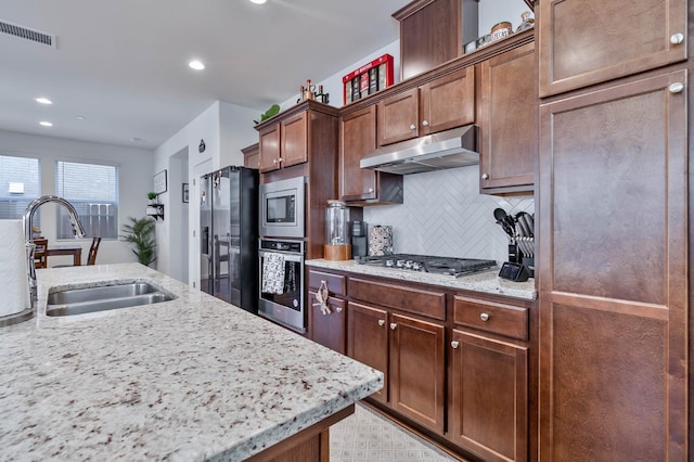 915 Winchell Way W, Madera, CA 93636 - kitchen featuring stainless steel appliances, under cabinet range hood, decorative backsplash, light stone countertops, and recessed lighting