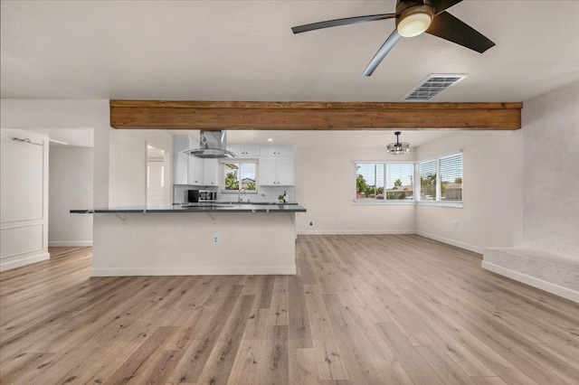 652 E Portals Ave, Fresno, CA 93710 - kitchen with white cabinets, beamed ceiling, dark countertops, light wood-type flooring, and a breakfast bar area