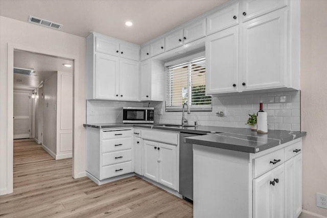 652 E Portals Ave, Fresno, CA 93710 - kitchen featuring white cabinets, appliances with stainless steel finishes, light wood finished floors, decorative backsplash, and dark countertops