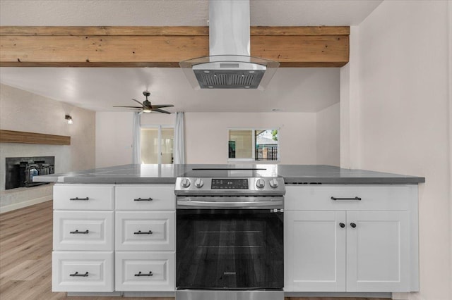 652 E Portals Ave, Fresno, CA 93710 - kitchen with electric range, island exhaust hood, open floor plan, white cabinets, and a wood stove