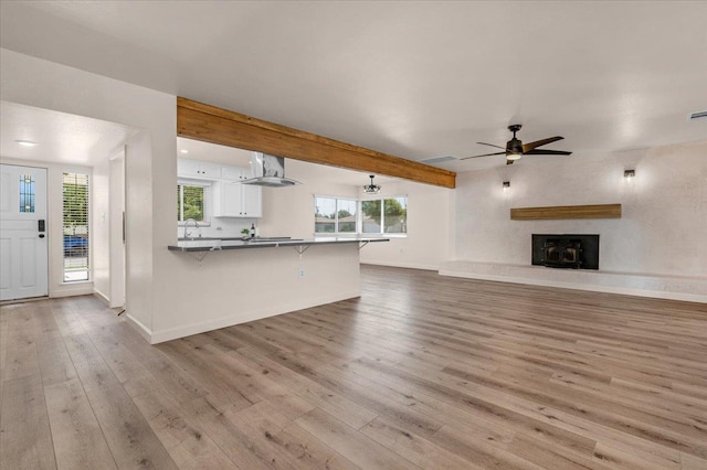 652 E Portals Ave, Fresno, CA 93710 - unfurnished living room with wood finished floors, ceiling fan, a fireplace with raised hearth, and beamed ceiling