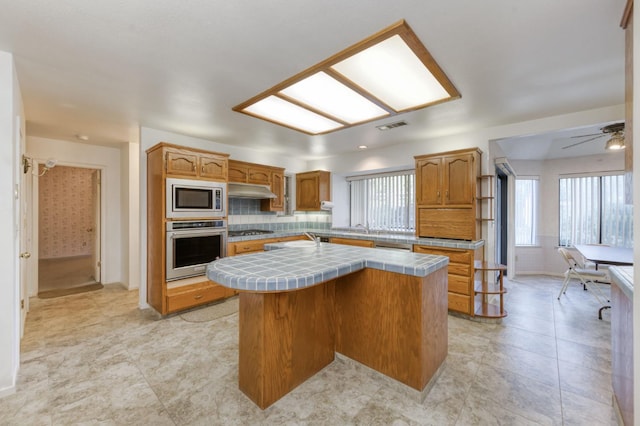 7664 N Kavanagh Ave, Fresno, CA 93711 - kitchen featuring stainless steel appliances, tile counters, a kitchen island, and plenty of natural light