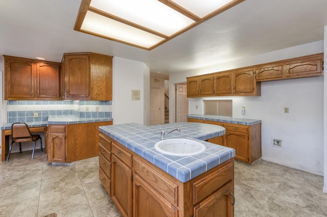 7664 N Kavanagh Ave, Fresno, CA 93711 - kitchen featuring tile countertops, brown cabinetry, decorative backsplash, and built in study area
