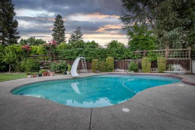 7664 N Kavanagh Ave, Fresno, CA 93711 - pool at dusk with a water slide, a fenced backyard, and a patio