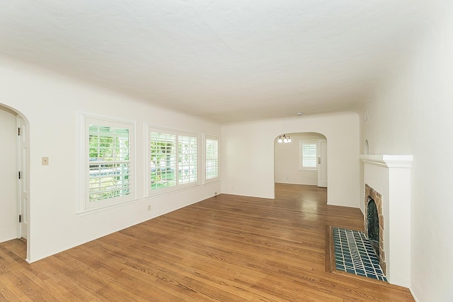 4845 Arcade Ave, Fresno, CA 93704 - unfurnished living room with arched walkways, light wood-style floors, and a fireplace
