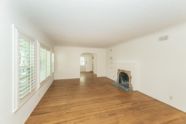 4845 Arcade Ave, Fresno, CA 93704 - unfurnished living room featuring arched walkways, light wood-style floors, and a fireplace with flush hearth