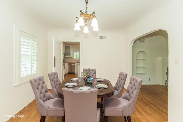 4845 Arcade Ave, Fresno, CA 93704 - dining room featuring a chandelier, arched walkways, light wood-style flooring, and built in shelves