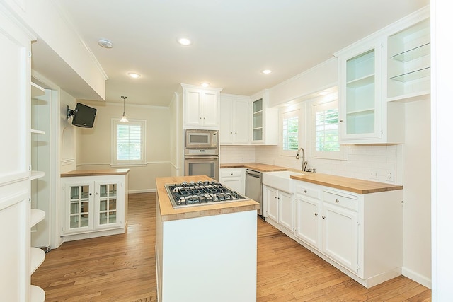 4845 Arcade Ave, Fresno, CA 93704 - kitchen with wooden counters, appliances with stainless steel finishes, a kitchen island, light wood finished floors, and backsplash