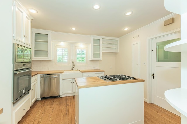 4845 Arcade Ave, Fresno, CA 93704 - kitchen featuring butcher block countertops, stainless steel appliances, light wood-style floors, tasteful backsplash, and ornamental molding