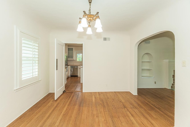 4845 Arcade Ave, Fresno, CA 93704 - unfurnished room featuring a chandelier, built in features, light wood-style floors, and arched walkways