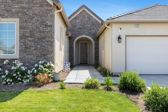 2421 N Cabrenet Pl, Hanford, CA 93230 - property entrance featuring stone siding, an attached garage, a lawn, and stucco siding