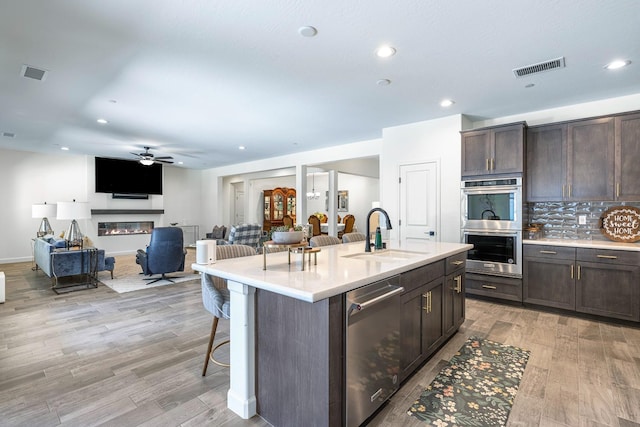 2421 N Cabrenet Pl, Hanford, CA 93230 - kitchen with appliances with stainless steel finishes, dark brown cabinets, light wood-style floors, a kitchen bar, and recessed lighting
