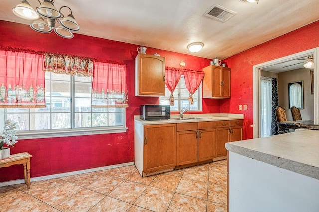 1830 Valeria St, Dos Palos, CA 93620 - kitchen featuring black microwave, light countertops, brown cabinets, and light tile patterned floors