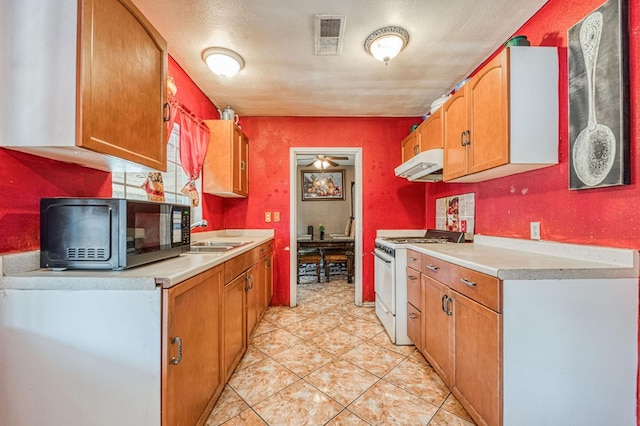 1830 Valeria St, Dos Palos, CA 93620 - kitchen with white gas range, under cabinet range hood, light countertops, and light tile patterned flooring