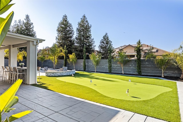 7160 W Dovewood Ln, Fresno, CA 93723 - view of property's community with an area to practice putting, a patio area, a fenced backyard, and an outdoor fire pit