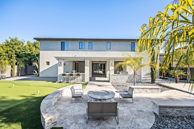 7160 W Dovewood Ln, Fresno, CA 93723 - rear view of house featuring stucco siding, a putting area, an outdoor fire pit, a patio, and a ceiling fan