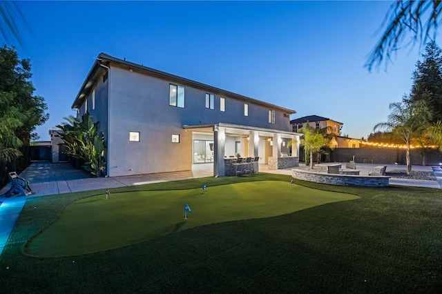 7160 W Dovewood Ln, Fresno, CA 93723 - back of property featuring a patio, a putting area, stucco siding, and a fire pit
