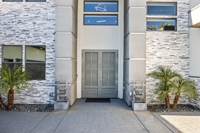 7160 W Dovewood Ln, Fresno, CA 93723 - view of exterior entry with stucco siding, stone siding, and french doors