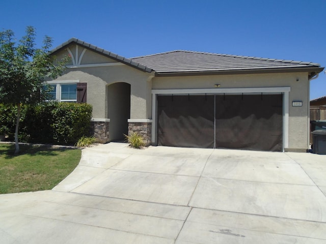 6908 E Castle Ave, Fresno, CA 93727 - view of front of home featuring driveway, an attached garage, stucco siding, a tile roof, and stone siding