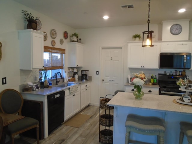 6908 E Castle Ave, Fresno, CA 93727 - kitchen with black dishwasher, stainless steel electric range oven, white cabinetry, a breakfast bar, and wood finished floors