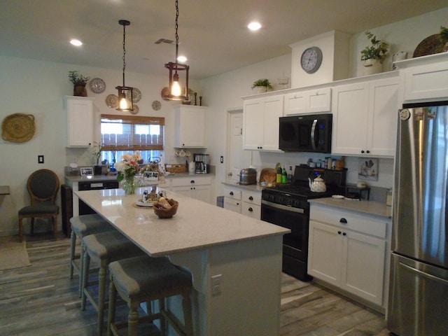 6908 E Castle Ave, Fresno, CA 93727 - kitchen with freestanding refrigerator, black microwave, gas stove, a kitchen island, and white cabinetry