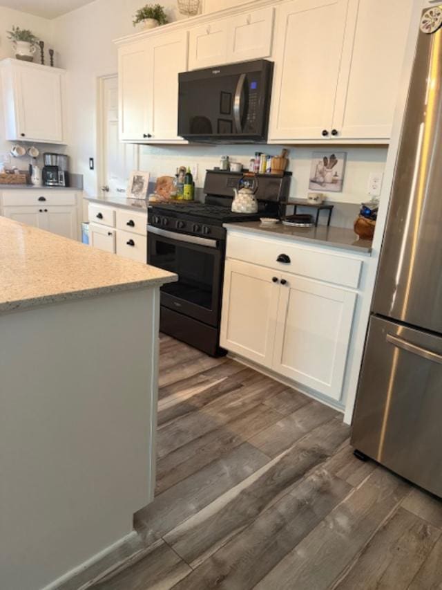 6908 E Castle Ave, Fresno, CA 93727 - kitchen with black microwave, freestanding refrigerator, gas range oven, and dark wood-type flooring