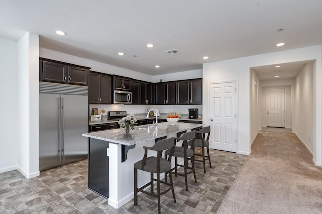 7173 N Shiraz, Fresno, CA 93722 - kitchen with stainless steel appliances, light stone counters, a kitchen breakfast bar, recessed lighting, and a center island with sink