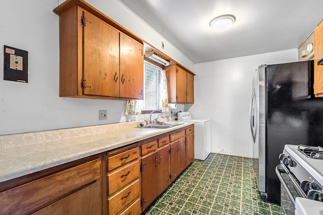 8573 E Ostler St, Selma, CA 93662 - kitchen with range with gas stovetop, dark floors, brown cabinets, light countertops, and washing machine and clothes dryer