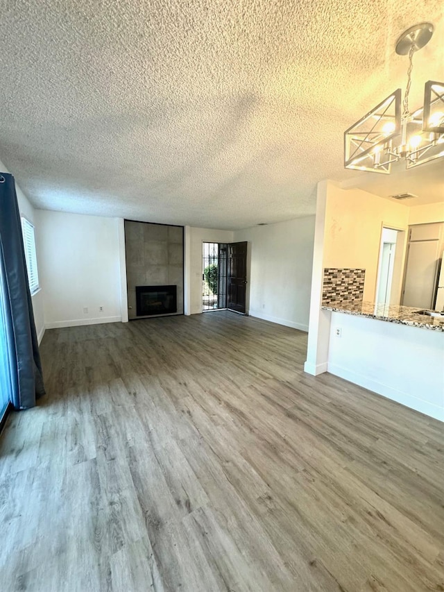 1151 S Chestnut Ave Unit 108, Fresno, CA 93702 - unfurnished living room with wood finished floors, a textured ceiling, a fireplace, and a chandelier