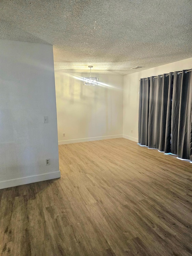 1151 S Chestnut Ave Unit 108, Fresno, CA 93702 - empty room with wood finished floors, a textured ceiling, and a chandelier