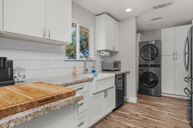 27762 Twin Ponds Rd, Clovis, CA 93619 - kitchen with stacked washing machine and dryer, white cabinets, light wood finished floors, light stone countertops, and recessed lighting