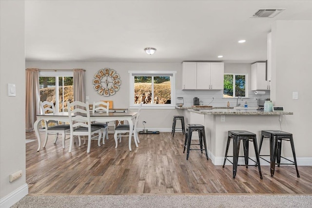 27762 Twin Ponds Rd, Clovis, CA 93619 - kitchen featuring a breakfast bar, white cabinets, healthy amount of natural light, wood finished floors, and recessed lighting
