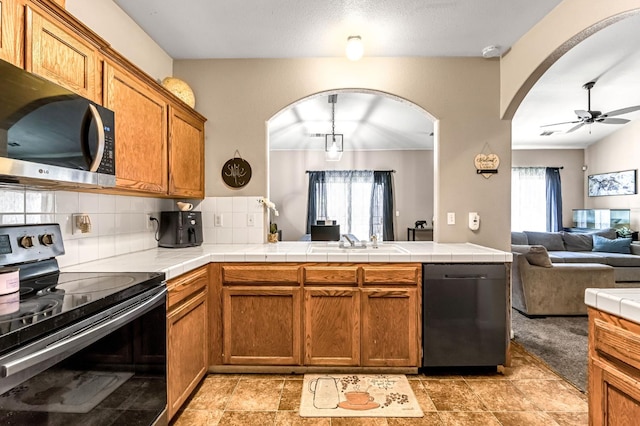 3615 W Michigan Ave, Fresno, CA 93722 - kitchen featuring stainless steel appliances, open floor plan, arched walkways, brown cabinets, and backsplash