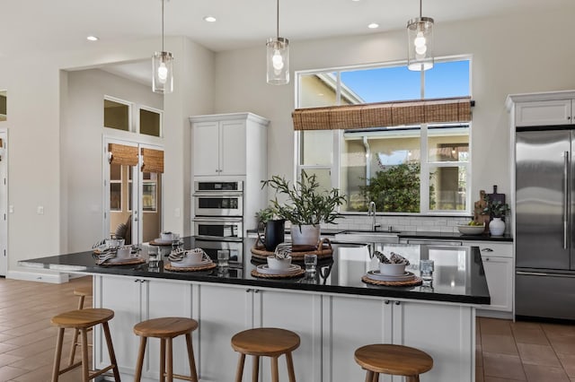 998 Highland Rd W, Madera, CA 93636 - kitchen with appliances with stainless steel finishes, dark countertops, a breakfast bar, white cabinets, and a high ceiling