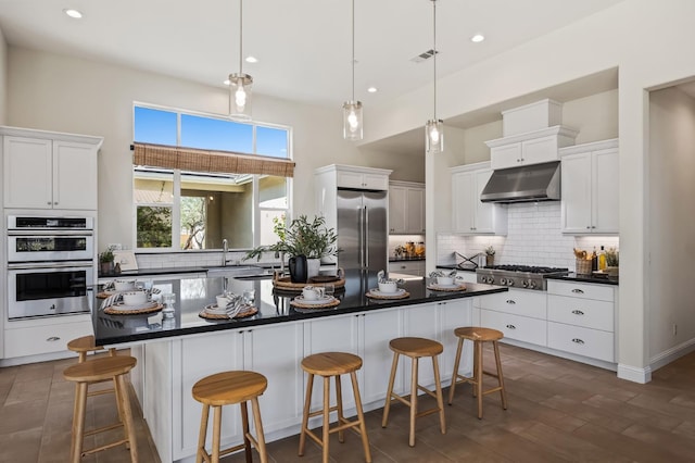 998 Highland Rd W, Madera, CA 93636 - kitchen featuring appliances with stainless steel finishes, under cabinet range hood, dark countertops, decorative backsplash, and white cabinetry