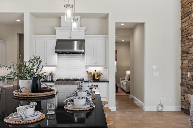 998 Highland Rd W, Madera, CA 93636 - kitchen with range hood, backsplash, white cabinets, stainless steel gas stovetop, and decorative light fixtures